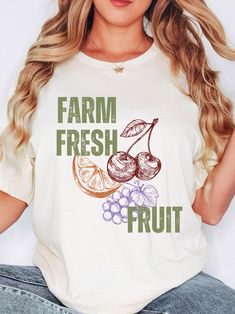 Step back in time with our charming "Farm Fresh Fruit" vintage t-shirt, featuring beautiful illustrations of a cherry, orange, and grapes. This shirt combines the nostalgia of a garderning era, farmer markert goer, foodie, or lover of fresh fruit, with modern comfort, making it a perfect trendy graphic t- shirt addition to any casual wardrobe. Product Details: This classic unisex jersey short sleeve tee fits like a well-loved favorite. Soft cotton and quality print make users fall in love with i Organic Short Sleeve T-shirt For Spring, Organic White Graphic Print Tops, Vintage Fruit Print Crew Neck Tops, Vintage Crew Neck Tops With Fruit Print, Vintage Fruit Print Top For Summer, Vintage Cotton Tops With Fruit Print, Vintage Summer Top With Fruit Print, Cottagecore Printed T-shirt With Relaxed Fit, Organic White T-shirt For Summer