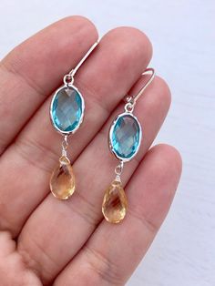 Citrine and Blue Topaz Earrings, Yellow and Blue Statement Earrings, November Birthstone, Citrine Jewelry in Gold or Silver, Gift for her These rich and colorful earrings feature 15 mm faceted blue topaz oval stones bezel set in 14k Gold filled or sterling silver. Suspended from them are 10mm natural yellow citrine faceted teardrops. The earrings come in lever back ear wires in the finish of your choice. These are perfect light weight earrings with a unique color combination in light blue and ye Blue Topaz Teardrop Earrings, Blue Topaz Earrings With Gemstone Accents, Blue Topaz Dangle Earrings, Blue Topaz Jewelry Set With Earrings, Blue Statement Earrings, Silver Gift Wrap, Citrine Jewelry, Blue Topaz Earrings, Yellow Citrine