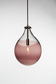 a pink and brown glass light hanging from a ceiling fixture with a black cord attached to it