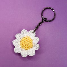 a crocheted flower keychain on a purple background