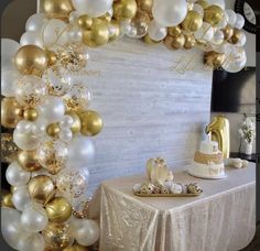 a table with gold and white balloons on it