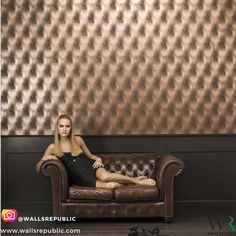 a woman sitting on top of a couch in front of a wall with gold foil