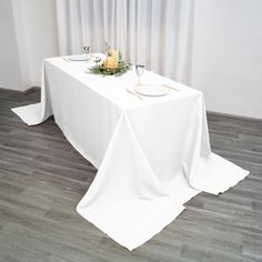 the table is set with white linens and place settings for two people to sit at