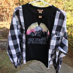 a black and white checkered shirt hanging on a clothes rack with trees in the background