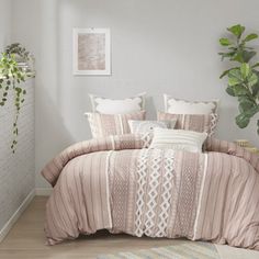 a bed in a bedroom with pink comforter and pillows