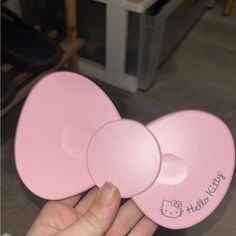 a person holding two pink plates with hello kitty written on them in front of a chair