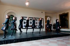 a group of women standing on top of a stage in front of a wall with pictures