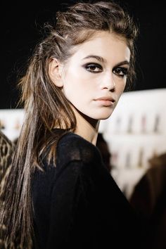 a woman with long hair and black eyeliners on the catwalk at a fashion show