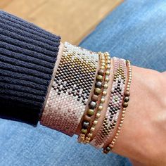 a woman's arm with four bracelets on it and one has gold beads