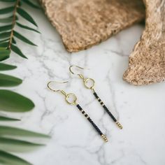 Experience sleek simplicity with our glass seed bead hook earrings. This chic linear design adds a subtle yet edgy accent to your look, featuring delicate black and gold seed beads. Elevate your style with minimalist flair. Minimalist Drop Earrings With Dangling Beads, Minimalist Beaded Dangle Earrings, Minimalist Adjustable Earrings With Dangling Beads, Minimalist Beaded Drop Earrings, Minimalist Adjustable Earrings With Tiny Beads, Minimalist Tiny Beads Drop Earrings, Minimalist Drop Earrings With Tiny Beads, Minimalist Dangle Earrings With Tiny Beads, Minimalist Black Linear Drop Earrings