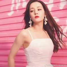 a woman in white dress standing next to pink wall with graffiti on it's side