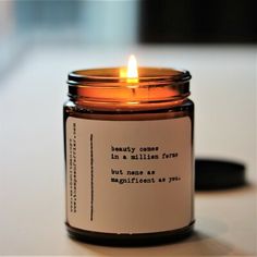 a candle that is sitting on a table with a quote written in the jar next to it