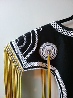 a black and white dress with gold tassels hanging from it's back