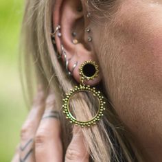 a close up of a person wearing ear rings and piercings on their ears,