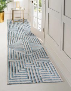 a blue and white area rug on the floor next to an open door with potted plants