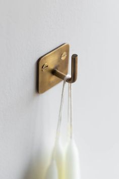 two white vases are hanging on the wall and one is holding a brass hook