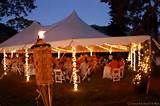 a large tent with white chairs and string lights on the sides is lit up at night