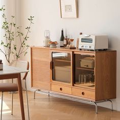 a wooden cabinet with glass doors in a living room next to a table and chair