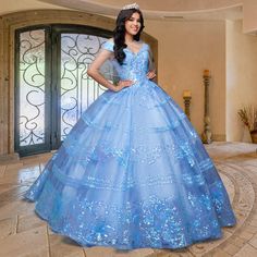 From the designers at QuinceGirl, this beautiful sequin quinceanera dress sparkles like sunshine in yellow or moonlight in blue. The off-the-shoulder quinceanera dress has sequin stripes and floral designs from the v-neckline to the hem. With regal flair, this traditional quince dress has a stylish fold-over collar with sparkly banded sleeves for an enchanting princess-inspired look. A back corset laces up for a comfortable fit on this fabulous sweetheart quinceanera gown, and layers of crinolin Gowns With Capes, Corset Quinceanera Dresses, Yellow Quince, Stripes And Floral, Cape Gown, Quince Dress, Blue Corset, Embellished Skirt, Birthday Fashion