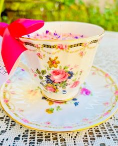 a tea cup with a red bow on it sitting on top of a saucer