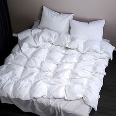 an unmade bed with white sheets and pillows