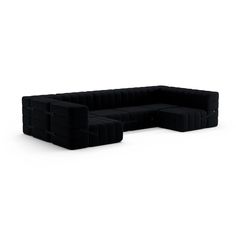 a large black couch sitting on top of a white floor next to a chair and ottoman