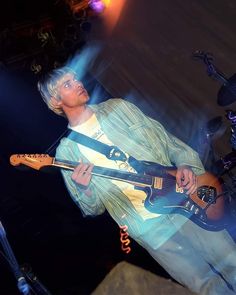 a young man playing an electric guitar on stage