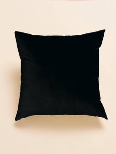 a black pillow sitting on top of a white wall