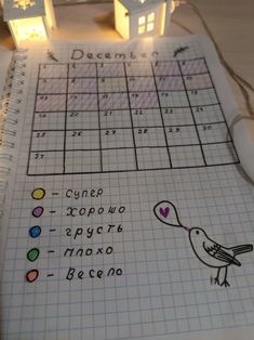 a notebook with a bird drawn on it next to two small houses and a pen