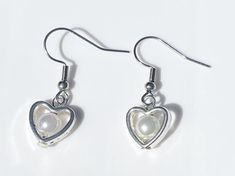 Add some coquette cuteness to your wardrobe with these stylish dangle earrings! Handcrafted from high-quality glass and steel materials, these unique earrings are the perfect whimsical everyday pair! With their complimentary colours and simple silver heart design, these earrings are perfect for adding a fun and trendy twist to any outfit.   Hooks are made from surgical steel, and are suitable for most sensitive ears. Lengths of earrings may vary within pairs. Domestic/Australian Standard shippin White Metal Heart Earrings, Pierced, White Metal Heart Earrings, White Metal Pierced Heart Earrings, Silver Pearl Earrings For Valentine's Day, White Metal Heart Earrings For Gift, White Metal Heart Earrings Gift, White Metal Earrings For Valentine's Day, Silver Heart-shaped Pearl Earrings For Gift, Valentine's Day White Metal Earrings