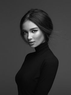 a black and white photo of a woman wearing a turtle neck top with her hair blowing in the wind