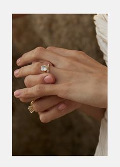 a woman's hand with two gold rings on her left and the other hand holding an engagement ring