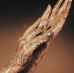 a woman's hand with gold glitter on it