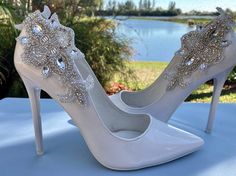 a pair of white high heeled shoes sitting on top of a blue cloth covered table