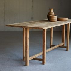 a wooden table with two vases on it and one sitting on the other side