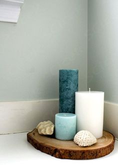 three candles sitting on top of a wooden table next to shells and seashells