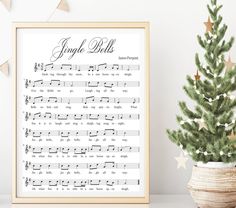 a christmas tree next to a framed sheet music score with the words angel bells on it