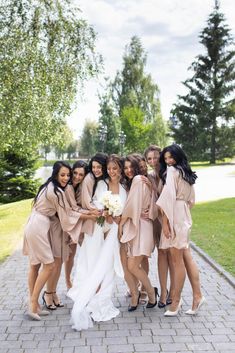 a group of women standing next to each other on a brick walkway in front of trees