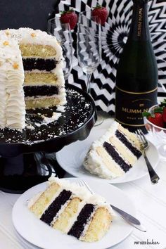 a slice of cake on a plate next to a wine bottle and two plates with desserts