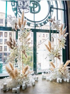 there are many vases with flowers and candles in front of the window on the table