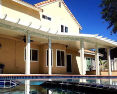 a house with a pool in front of it and an attached pergolated roof