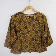 "Kenneth Mitchell Vintage Short Sleeve Floral / Paisley Shirt Gold, Green Purple Shoulder Pads Rayon Acetate Size: 24 Pit to Pit: 20\" Length: 26\"" Brown Paisley Print Summer Tops, Summer Brown Paisley Print Tops, Vintage Long Sleeve Paisley Print Top, Vintage Relaxed Fit Top With All Over Print, Vintage Long Sleeve Top With Paisley Print, Vintage Multicolor Paisley Print Tops, Fall Paisley Print Top With Relaxed Fit, Casual Brown Paisley Print Tops, Relaxed Fit Paisley Print Top For Fall