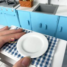 a person's hand on a white plate with blue cabinets in the background