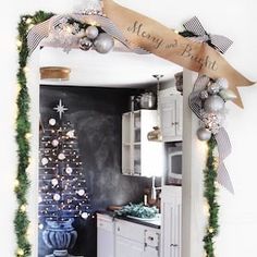 a kitchen decorated for christmas with garland and ornaments on the wall, along with a chalkboard sign that says merry to the people