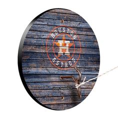 a round wooden sign hanging from a rope on the side of a building with an orange and white star painted on it