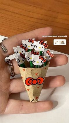 a hand holding an origami cone with hello kitty stickers on it's side