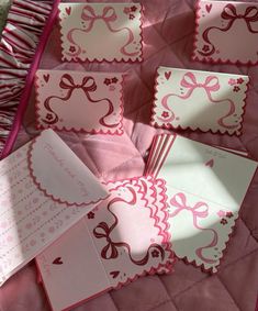 pink and white cards with bows on them are laying on a quilted bed spread