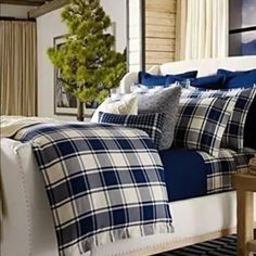 a bed with blue and white plaid comforter in a bedroom next to a window