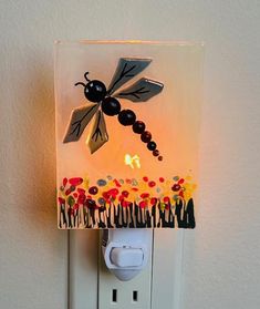 a light that is on the side of a wall with a dragonfly decoration above it