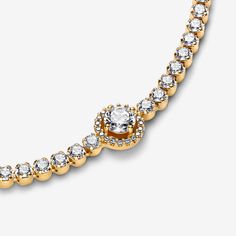 Level up your outfit with the Sparkling Halo Tennis Bracelet. Finished in elegant 14k gold plating, this hand-finished piece is decorated with sparkling stones. The centerpiece features a big central stone surrounded by a halo of clear cubic zirconia. There’s a small stone detail at the end of the chain for added sparkle. This tennis bracelet includes a lobster clasp for safe closure. Style with other shimmering Pandora Timeless pieces for a classic look that stands out. - Pandora Sparkling Halo Tennis Bracelet - 14k Gold-plated unique metal blend / Cubic Zirconia / Clear - Sz. 7.1 in Dazzling Jubilee Bracelet Jewelry Gift, Dazzling Jubilee Bracelet, Sparkling Cubic Zirconia Yellow Gold Diamond Bracelet, Sparkling Yellow Gold Cubic Zirconia Diamond Bracelet, Adjustable Yellow Gold Jewelry With Sparkling Stones, Dazzling Cubic Zirconia Jewelry With Jubilee Bracelet, Dazzling Cubic Zirconia Jubilee Bracelet, Gold Bracelet With Sparkling Cubic Zirconia Stones, Classic Yellow Gold Diamond Bracelet With Sparkling Stones